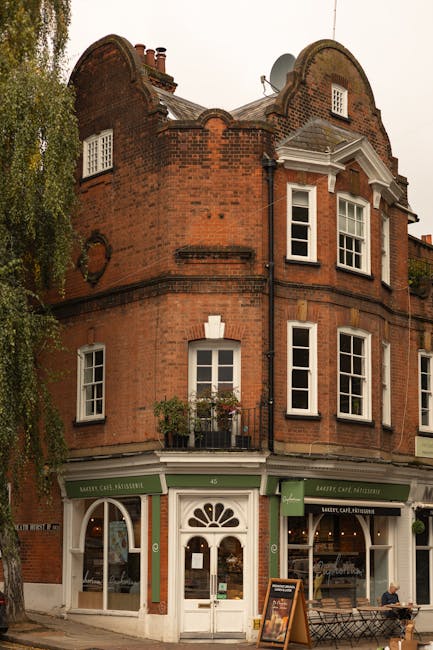 Two professional cleaners from Cleaner Hampstead are preparing cleaning equipment outdoors on a paved area. One cleaner, wearing a cap and uniform, is adjusting a portable vacuum cleaner with a large 